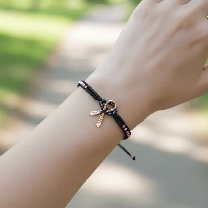 Copper Ribbon Black Pink Braided Breast Cancer Bracelet worn on a wrist in a natural setting.