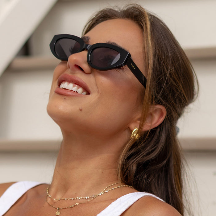lifestyle - female wearing diff eyewear x jessie james decker crystal cat eye sunglasses with a black acetate frame and grey polarized lenses angled view