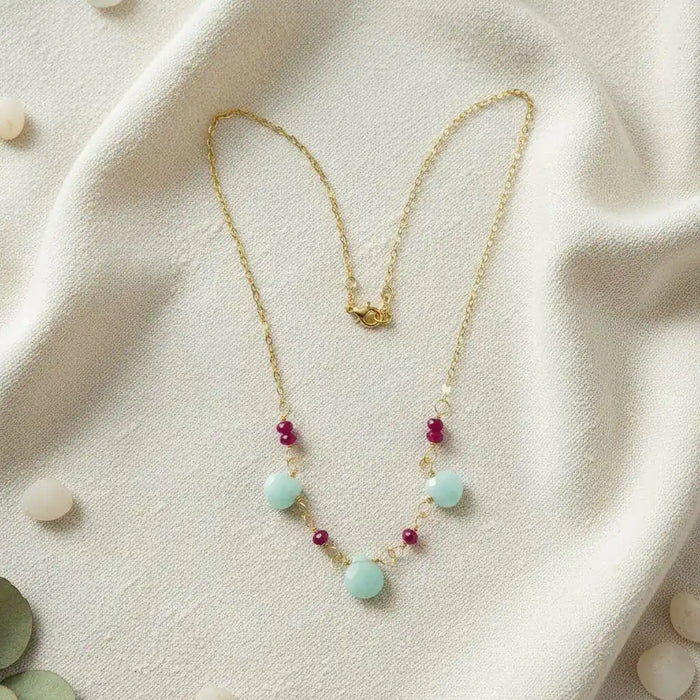 Dainty Gold Chain Mint and Hot Pink Gemstone Necklace on a soft fabric background with mint and hot pink gemstones.