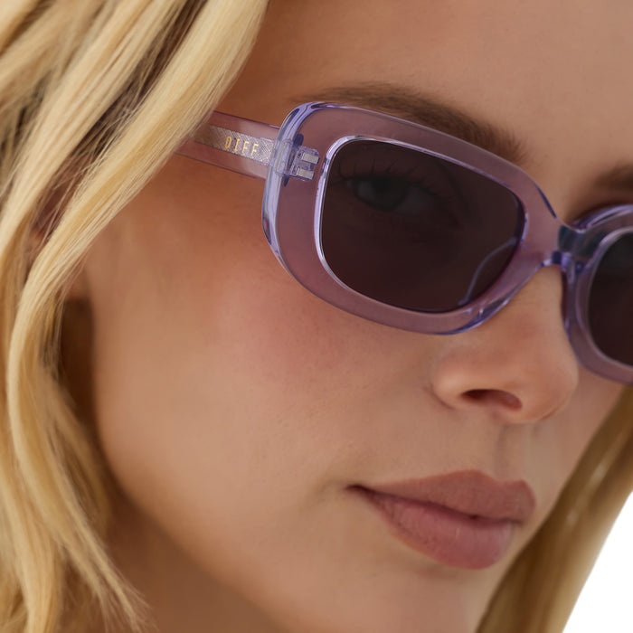 on model - female wearing diff eyewear daphne ii low profile square sunglasses with a lilac crystal purple acetate frame and grey lenses detailed view