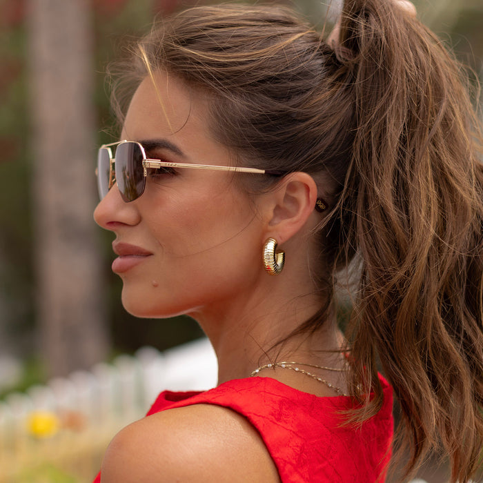 lifestyle - female wearing diff eyewear x jessie james decker destiny navigator sunglasses with a gold metal frame and dusk gradient lenses side view