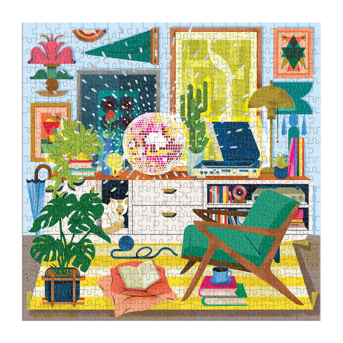 Once completed, the Disco Life 500 Piece Foil Puzzle by EurekartStudio displays a vibrant living room scene with plants, books, wall art, a record player, green chair, and yellow rug—combining modern elegance and retro style.