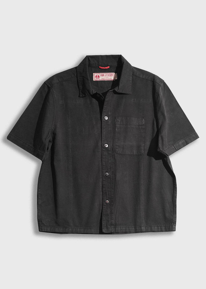Black short-sleeve button-up shirt with a front pocket on a white background. Iron & Resin label inside the collar.
