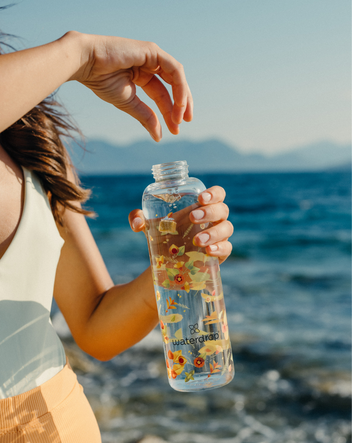 Edition Glass bottle held outdoors.
