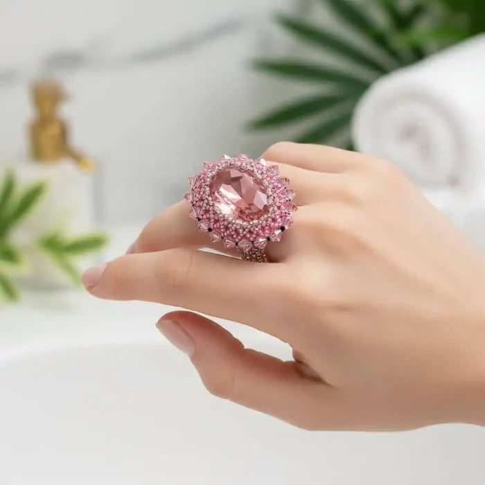 Epic Beaded Rose Crystal Bling Cocktail Ring showcasing a pink crystal on a hand against a blurred background.