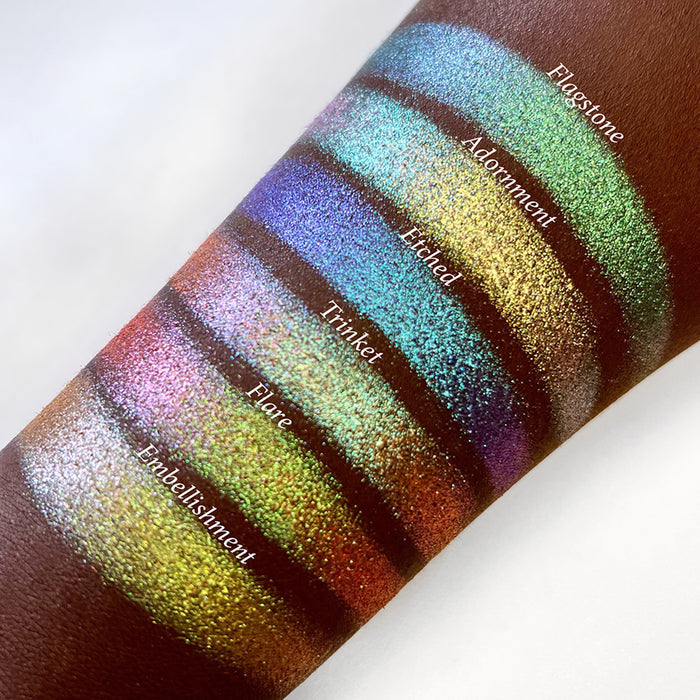 Top angled arm swatches on deep skin tone of Etched Glitter Multichrome Eyeshadow shifts compared to Flagstone, Adornment, Trinket, Flare and Embellishment