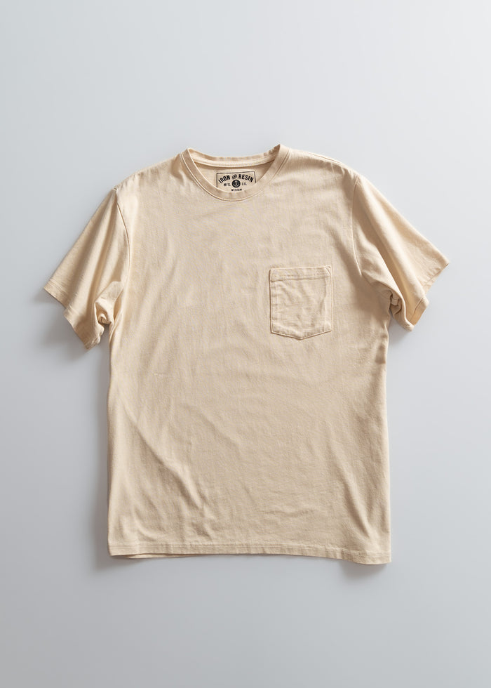 Beige T-shirt with a chest pocket on a light gray background, featuring a visible label inside the collar.