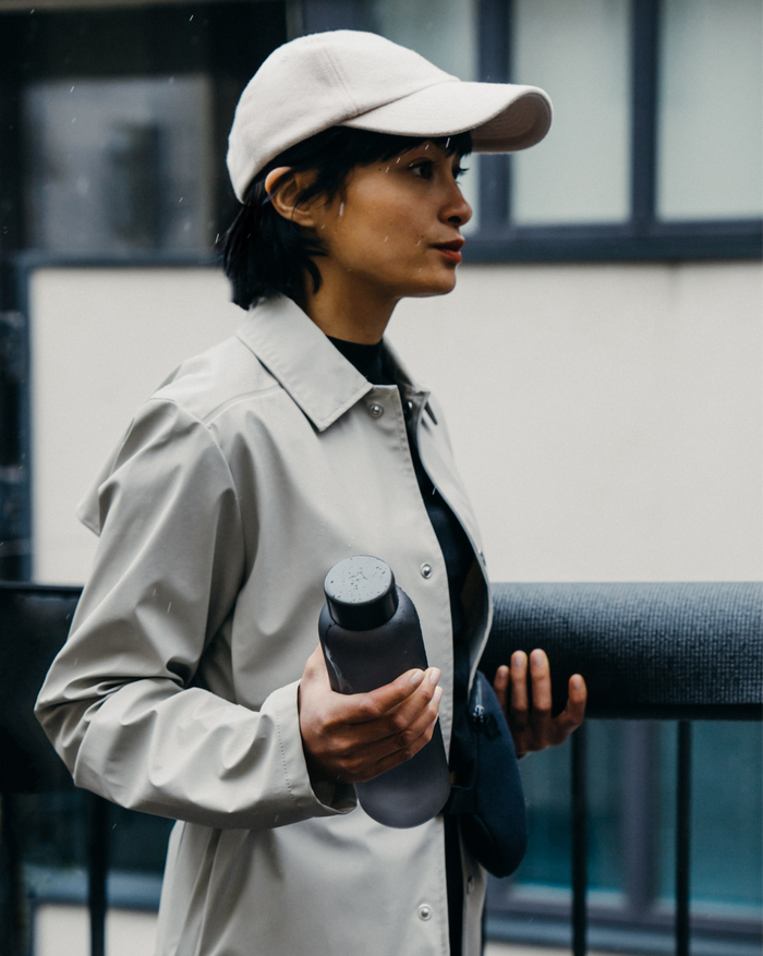 Woman in white hat and coat holding Frosted Glass water bottle.