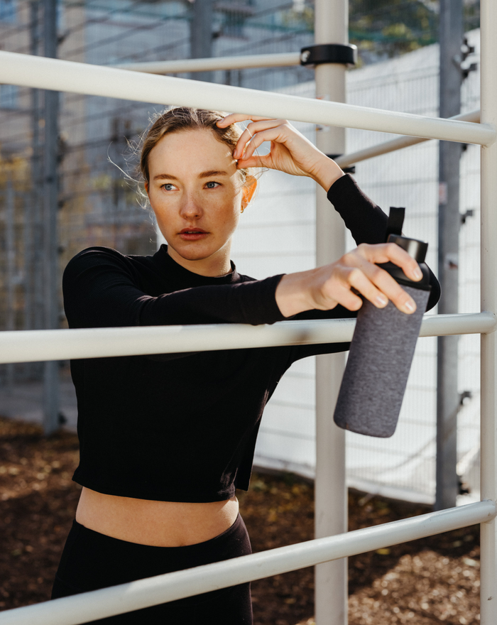A woman holding a Frosted Glass water bottle, showcasing its robust borosilicate material, perfect for durable and stylish hydration on the go.
