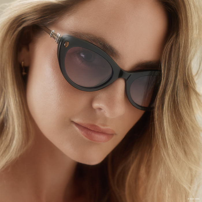 on model - blonde female wearing diff eyewear x practical magic 2 gillian cateye sunglasses with a black frame and purple gradient lenses angled view