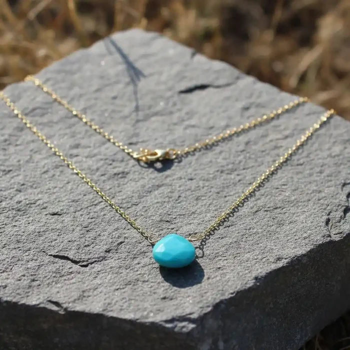 Gold Filled Aqua Jade Wire Wrap Gemstone Drop Necklace placed on a textured stone background.