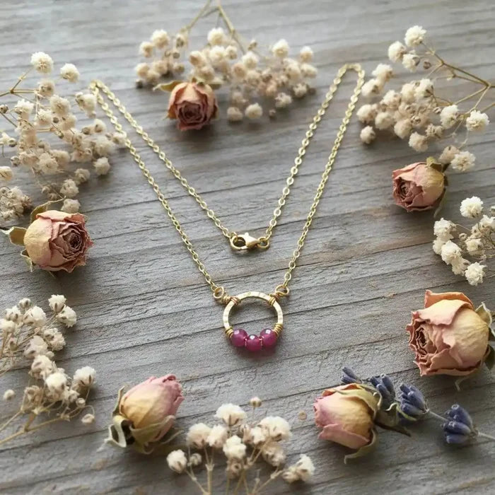 Gold Filled Pink Chalcedony Open Circle Necklace surrounded by dried roses and flowers.