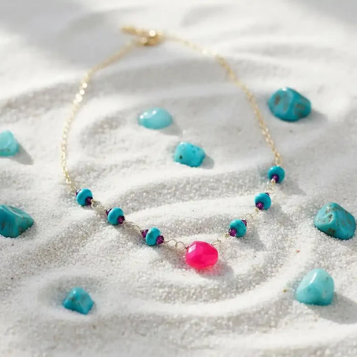 Gold Filled Pink Chalcedony Turquoise Gemstone Drop Necklace displayed among turquoise stones.