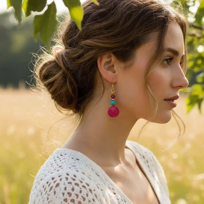 Woman wearing Gold Filled Wire Wrapped Pink And Aqua Gemstone Earrings in a field, showcasing vibrant colors and handmade elegance.