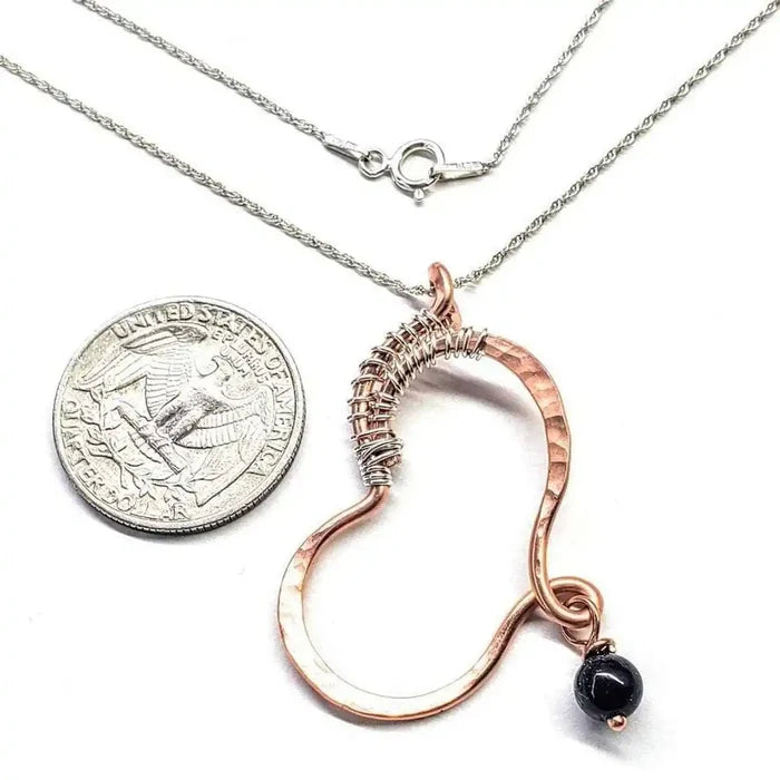 Hammered Copper Butterfly Wing Child Abuse Survivor Necklace with black Swarovski crystal and quarter for scale.