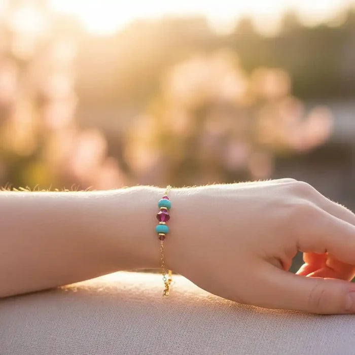 Handmade Gold Filled Pink Turquoise Gemstone Bracelet showcased on a hand with a blurred floral background.