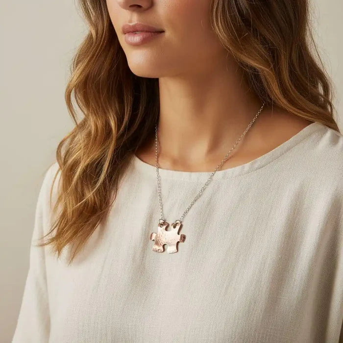 Necklace with a puzzle piece pendant worn by a person against a neutral background