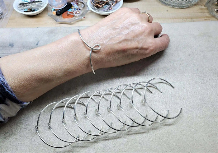 Handmade Wire Sculpted Silver Teardrop Bangle worn on wrist with multiple silver bangles displayed.