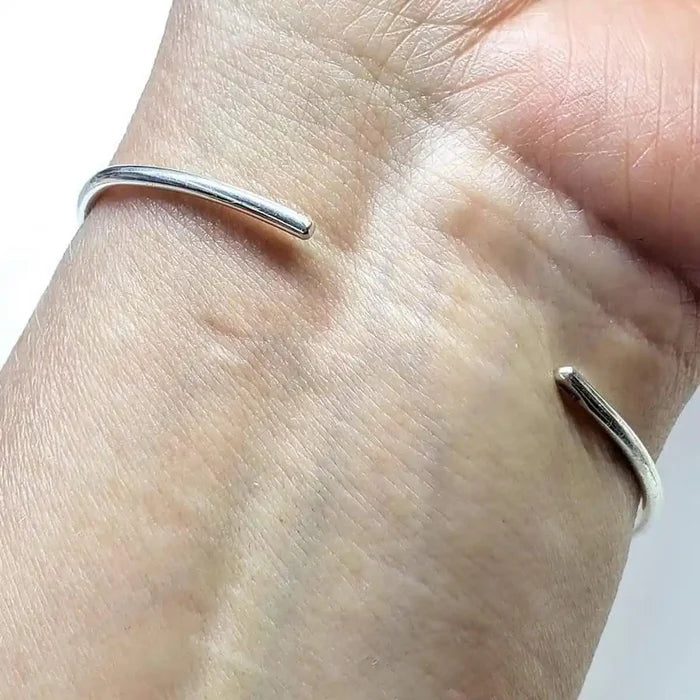 Handmade Wire Sculpted Silver Teardrop Bangle worn on a wrist, showcasing its elegant design and shiny finish.