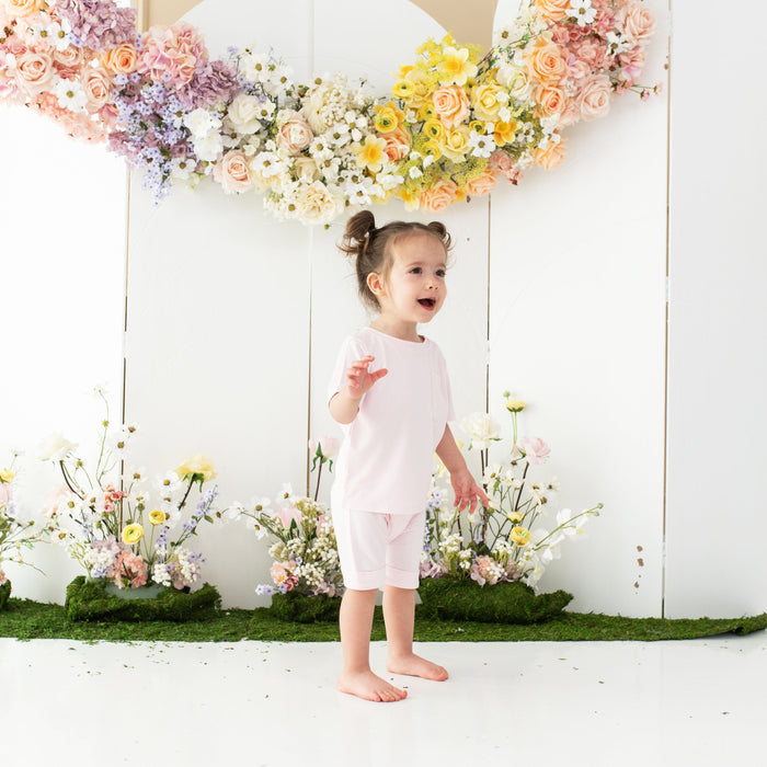 Toddler wearing Kyte Baby Harem Shorts with cuffed edges in Sakura