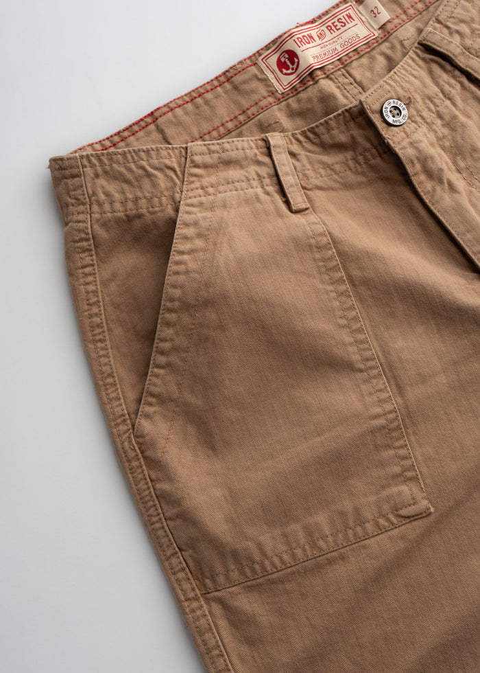 Close-up of brown Iron and Resin pants with visible label, button, and pocket detail on a white background.