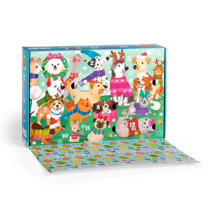 The Kathryn Selbert Ho Ho Howl! Countdown Puzzle Set is a festive 12-day advent calendar with illustrated dogs in holiday outfits, numbered doors, and a green snowflake background. The partially open calendar reveals a colorful flap.