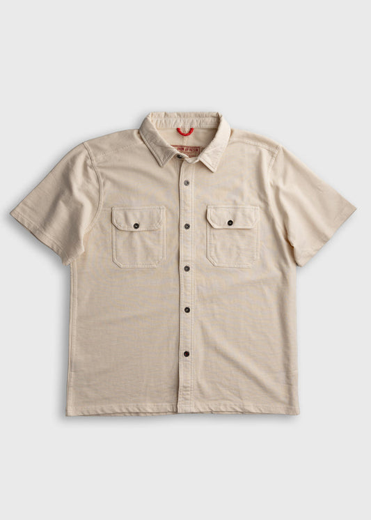 Beige short-sleeve shirt with button front and two chest pockets, laid flat on a white background.