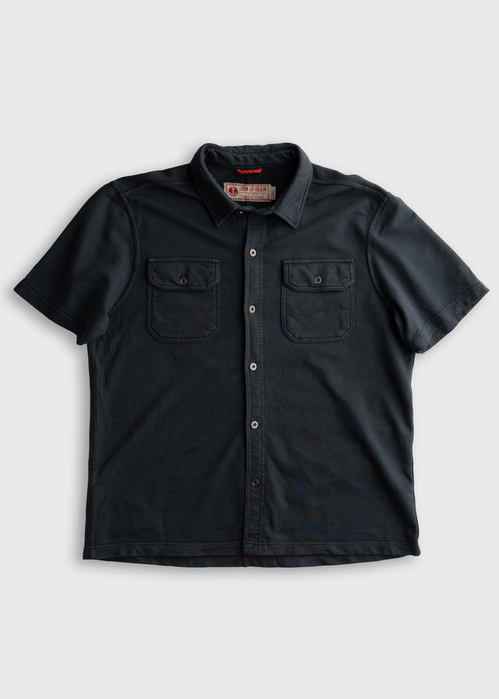 Dark short-sleeve button-up shirt with two chest pockets and a collar, displayed on a plain background.