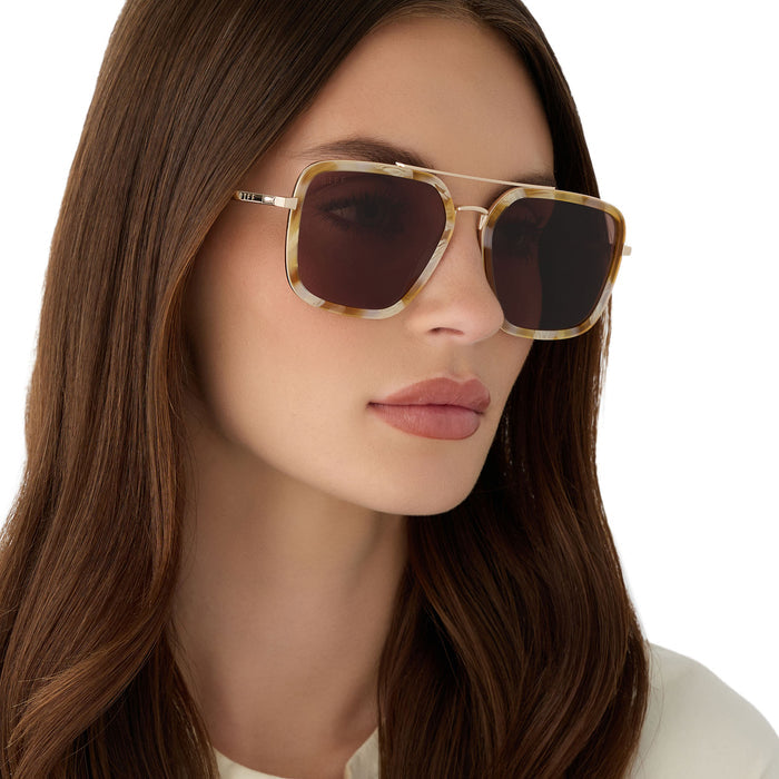 on model - female wearing diff eyewear jordan navigator sunglasses with a gilded tortoise acetate and gold metal frame with a brown lens angled view
