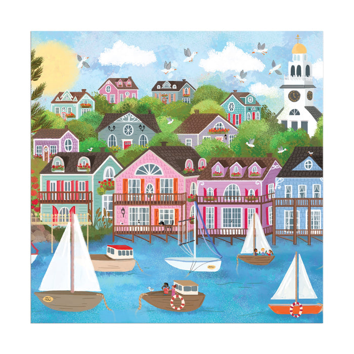 Enjoy assembling the Joy Laforme Harbor by the Sea 300 Piece Puzzle, featuring a colorful seaside village scene with sailboats, hillside houses, a white church tower, and people on a sunny day. From the brand Joy Laforme.