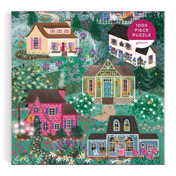 Illustration of four charming, colorful houses with lush gardens. The Joy Laforme The Cottage Hills 1000 Piece Puzzle in a Square Box captures vibrant greenery and cozy homes for a whimsical puzzling experience.