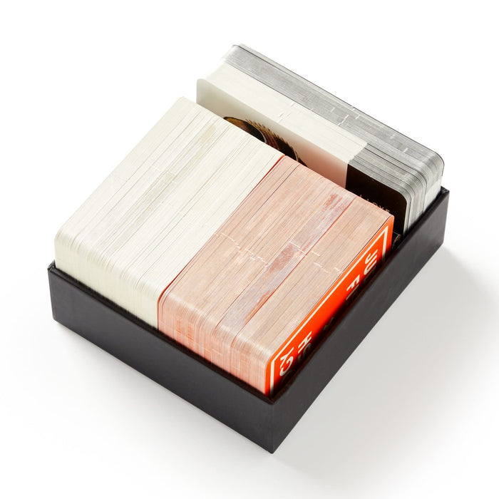 The Judgy Fish Game by Brass Monkey comes in a black box with three stacks of playing cards—white, red, and gray backs—perfect for parties or game nights. The cards are neatly organized and slightly spaced within the box.