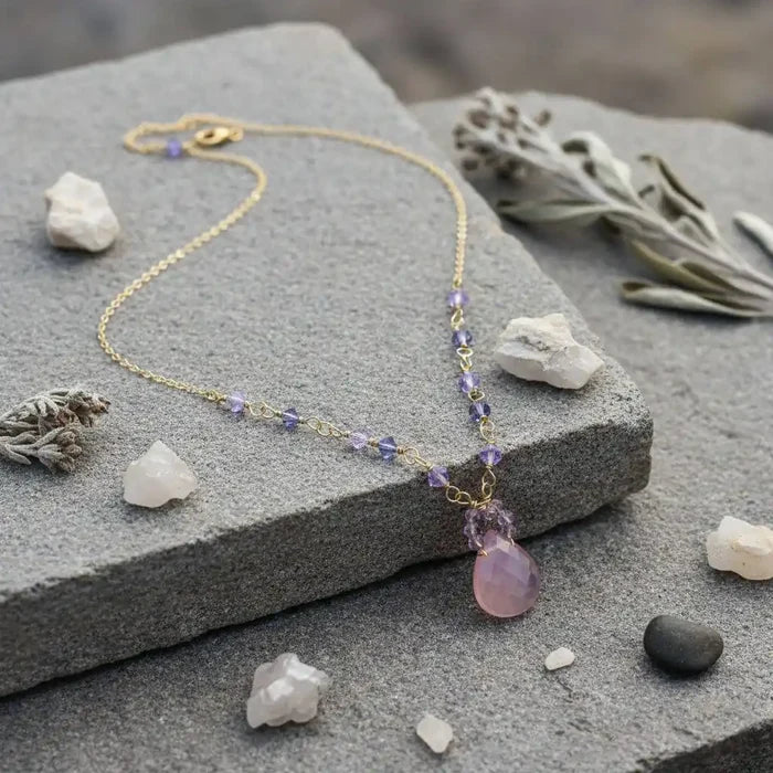 Purple Chalcedony Drop 14 KT Gold Filled Gemstone Necklace on a stone surface with decorative crystals.