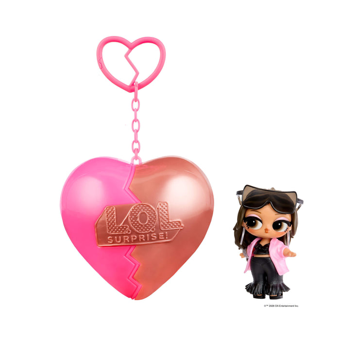 Small doll with short brown hair and sunglasses with a heart shaped keychain on a white background