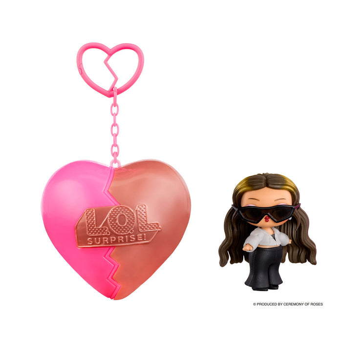 Small doll with brown hair and sunglasses with a heart shaped keychain on a white background