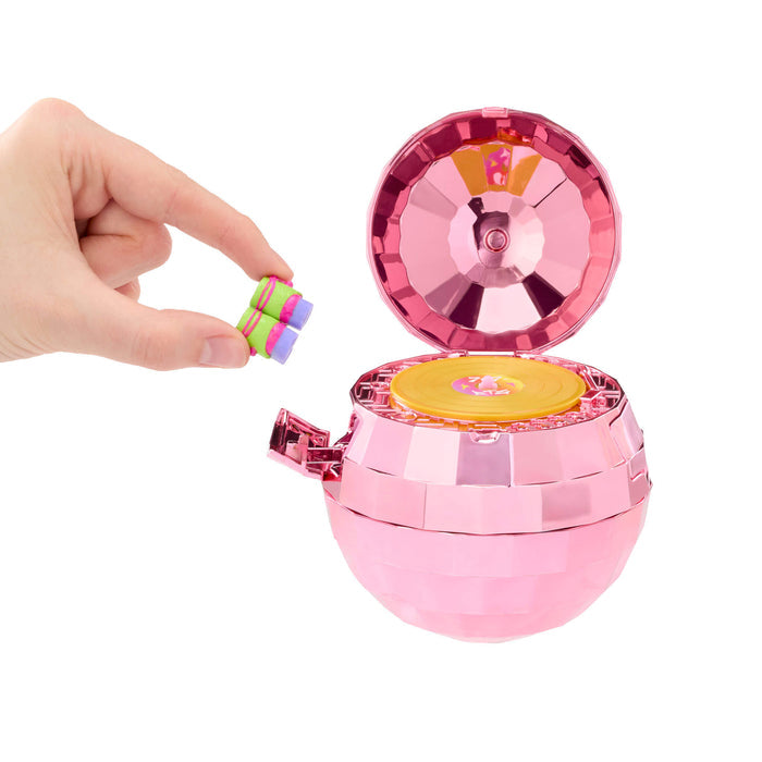 Hand by shiny pink ball with yellow disc in center on a white background