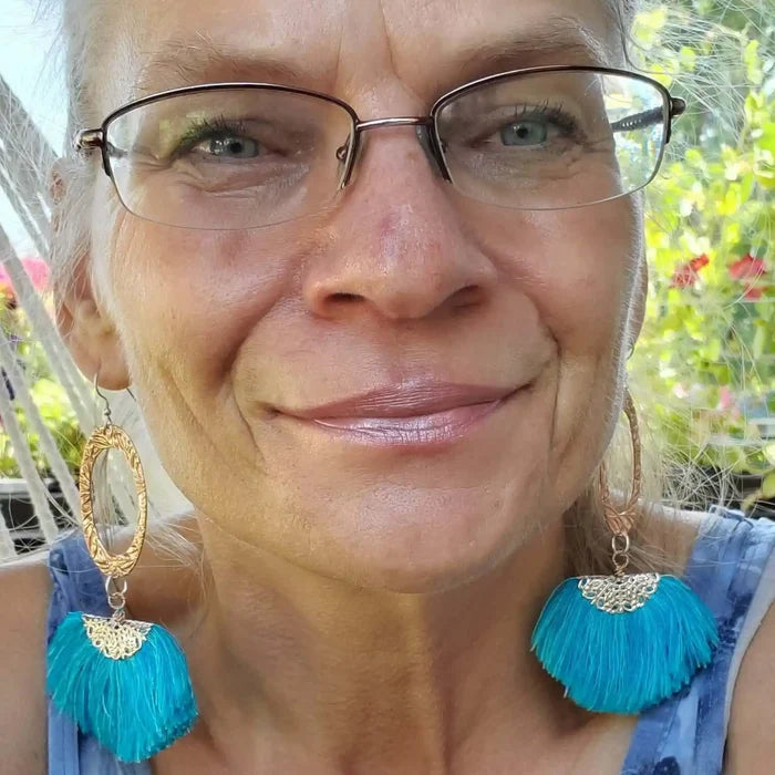 Long Copper Embossed Aqua Brushed Silk Fan Tassel Earrings worn by a woman with glasses, showcasing vibrant aqua tassels.