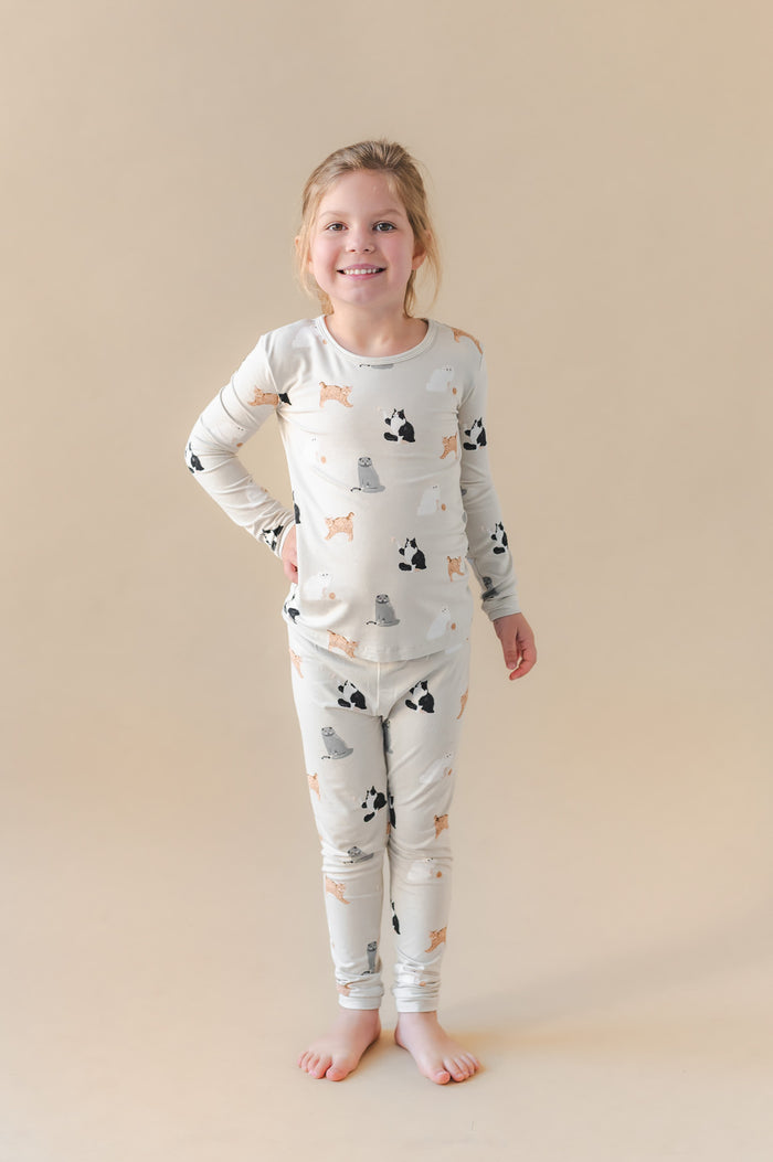 Young girl wearing a pajama set with cat prints on a beige background
