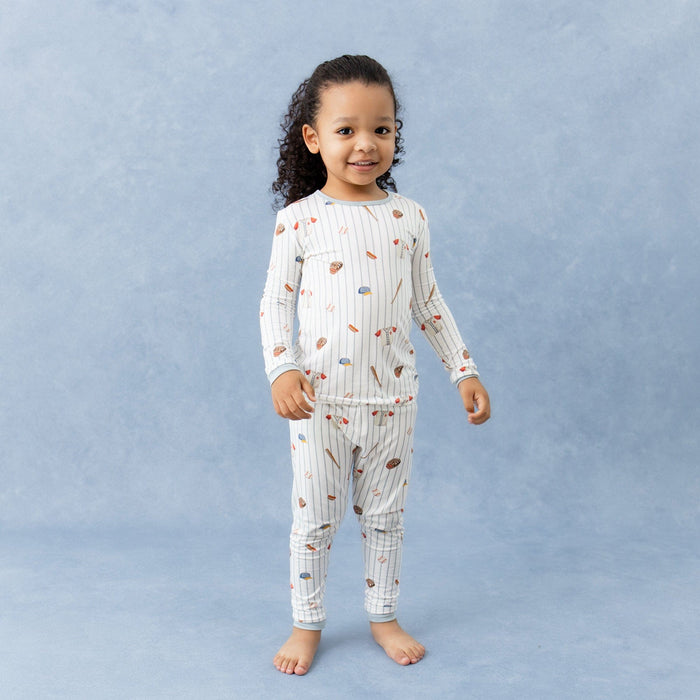 Young girl standing in front of a marbled background wearing the Long Sleeve Pajamas in Home Run