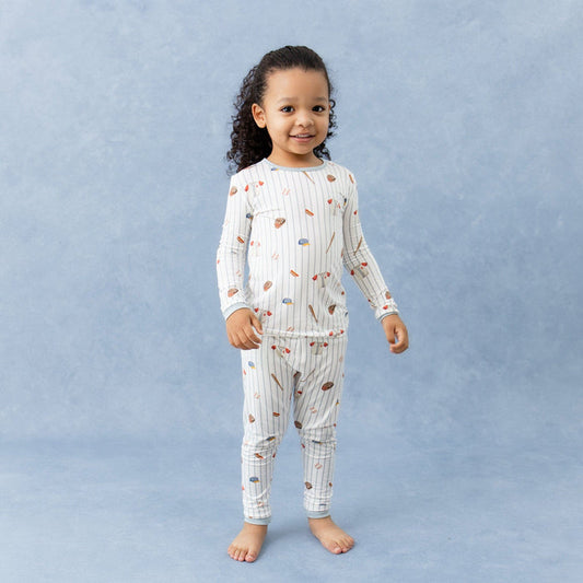 Young girl standing in front of a marbled background wearing the Long Sleeve Pajamas in Home Run