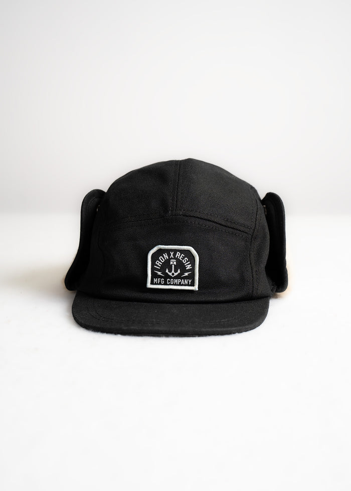 Black Iron & Resin cap with ear flaps, logo patch on front, displayed against a white background.
