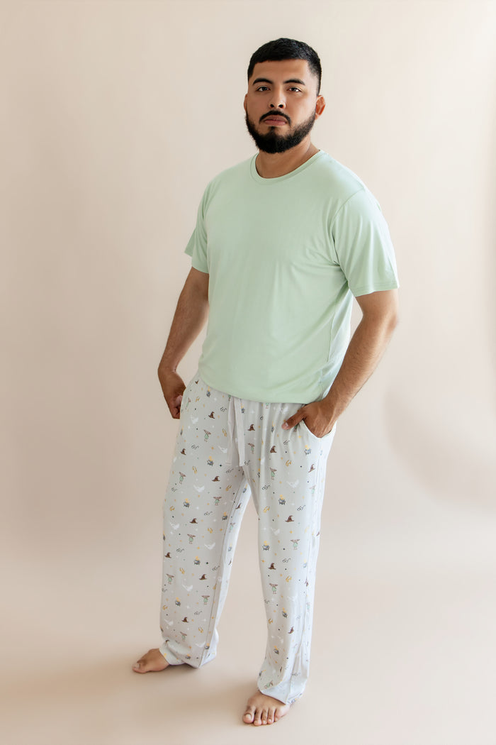 Person wearing a cream men's lounge pant with Harry Potter prints with green shirt on a beige background