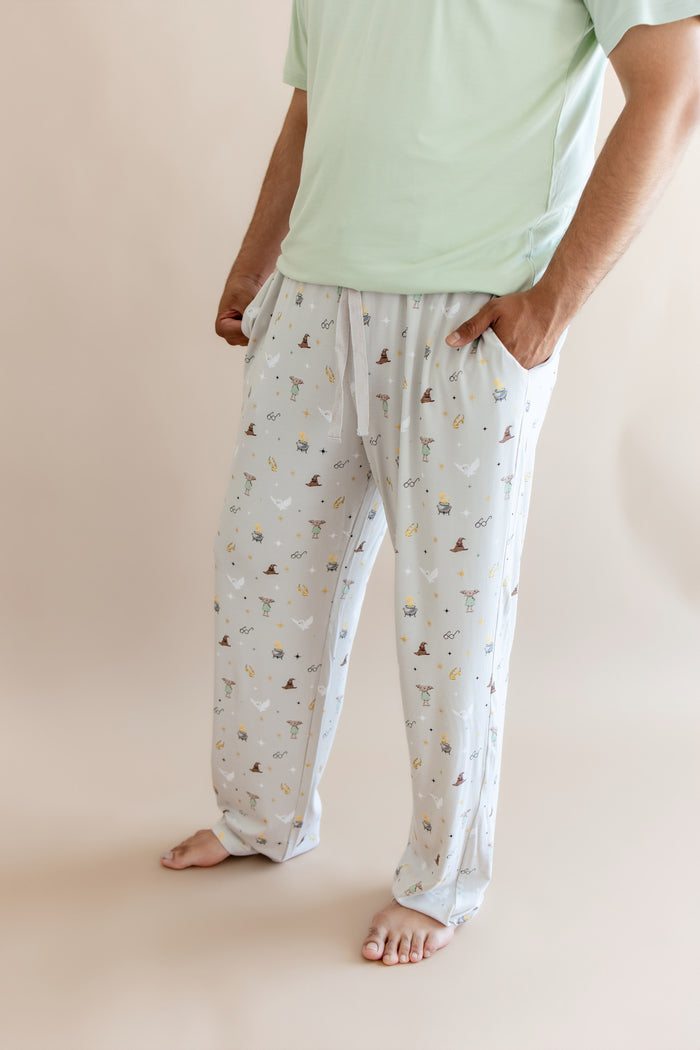 Person wearing cream men's lounge pant with pockets having Harry Potter prints with green shirt on a beige background