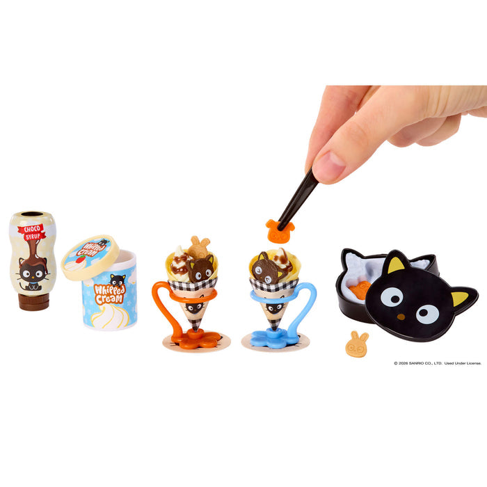 Set of small ice cream cone figurines with a hand interacting with one of them on a white background.