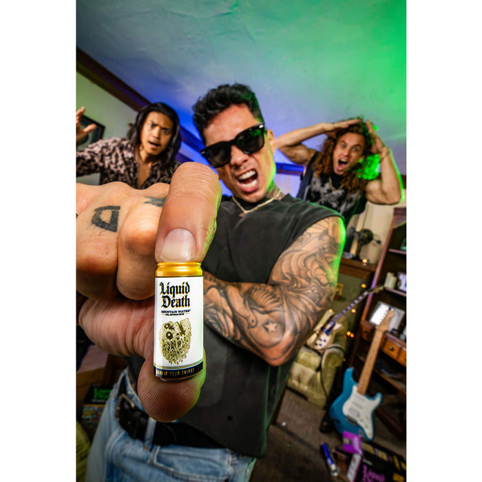 Person holding a 'Liquid Death' mini bottle with a colorful background