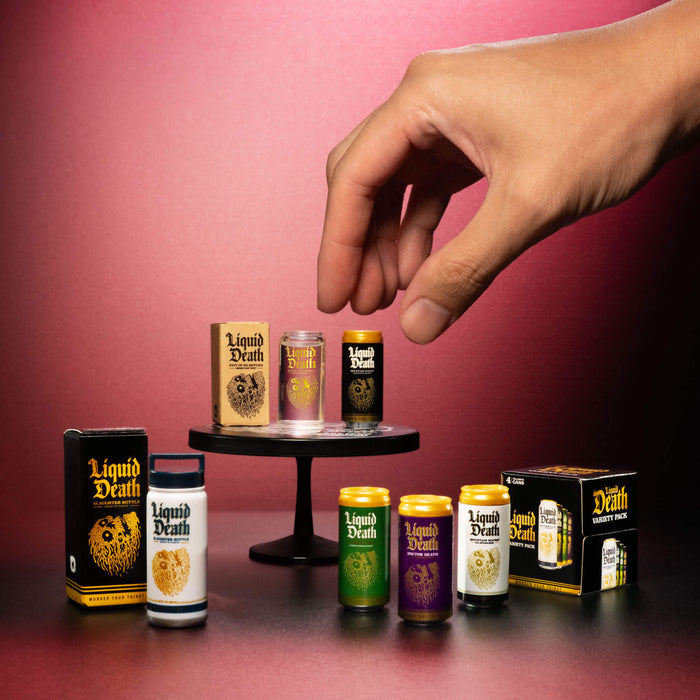 Hand reaching for a mini 'Liquid Death' product against a pink background