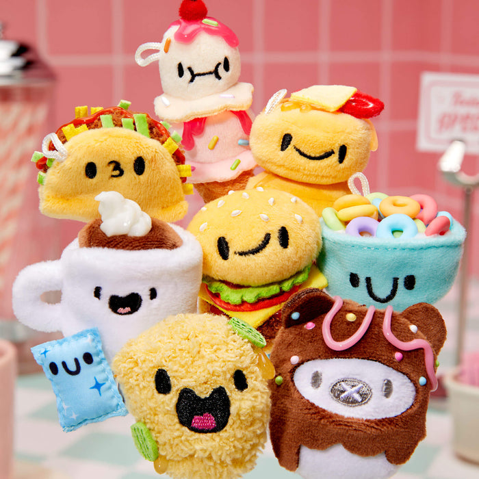 Collection of mini plush toys shaped like food items on a pink tiled wall background
