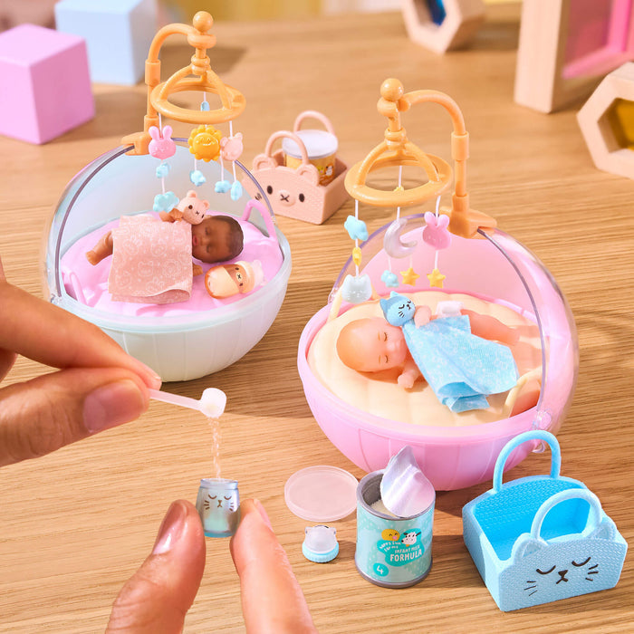 Mini Toy baby crib with baby dolls and accessories on a wooden surface