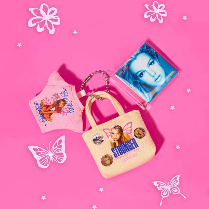 Small beige handbag with 'Stranger Then Yesterday' text, character key chain t-shirt, on a pink background with decorative elements.