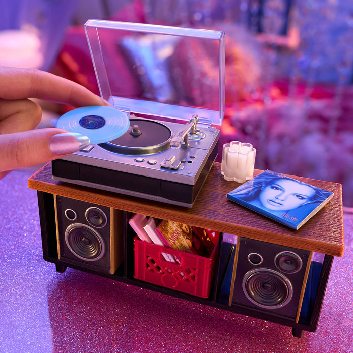 Miniature record player with turntable and speakers on a wooden surface.